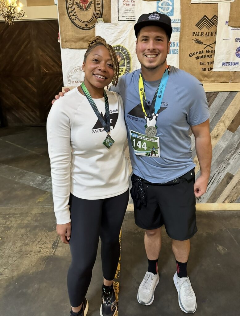 Vince wearing a race medal and bib, arm around a running friend.